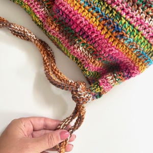 May include: A colorful crocheted bag with a brown and white drawstring.