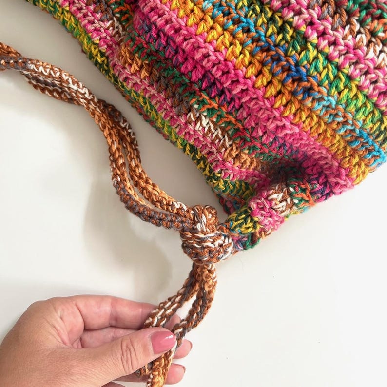May include: A colorful crocheted bag with a brown and white drawstring.