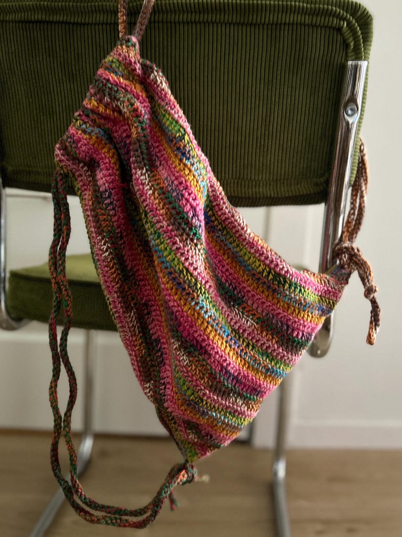 May include: A colorful striped crocheted drawstring bag with a long, knotted cord.