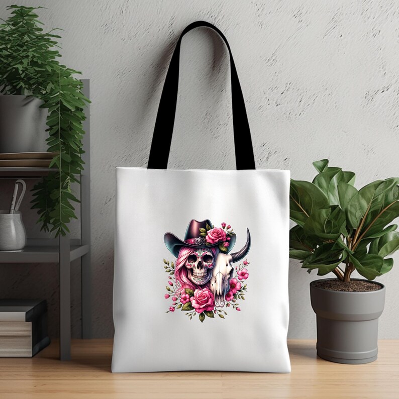 May include: White tote bag with a colorful skull wearing a cowboy hat and surrounded by pink flowers. The skull is wearing a pink wig and has a cow skull next to it.