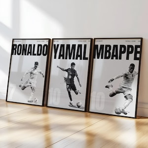 Może przedstawiać: Zestaw trzech oprawionych czarno-białych plakatów przedstawiających piłkarzy. Każdy plakat zawiera duże imię u góry, RONALDO, YAMAL i MBAPPE, z odpowiednim zdjęciem akcji sportowca kopiącego piłkę nożną poniżej.