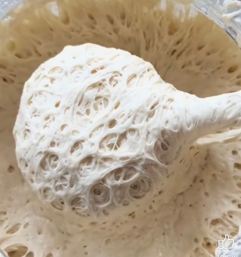 Pu&ograve; includere: Primo piano di un impasto bianco con una consistenza a rete. L'impasto viene sollevato con un cucchiaio, rivelando la sua consistenza ariosa ed elastica.