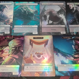 May include: Six Magic: The Gathering cards with holographic foil finishes. The cards feature various creatures, including a Kraken Horror, a Samurai, and a Zombie Dragon. The cards also include a Treasure artifact.