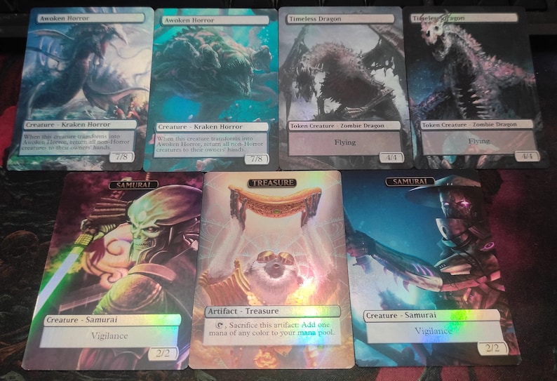 May include: Six Magic: The Gathering cards with holographic foil finishes. The cards feature various creatures, including a Kraken Horror, a Samurai, and a Zombie Dragon. The cards also include a Treasure artifact.