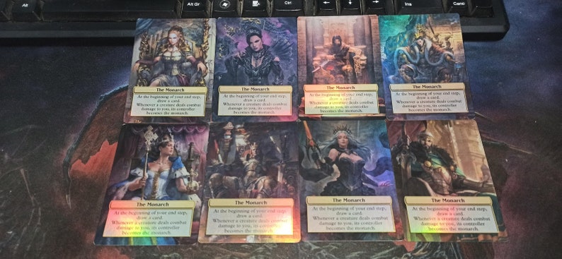 May include: Eight holographic playing cards with a rainbow sheen. Each card features a different character in a regal pose and the text "The Monarch" with the following text: "At the beginning of your end step, draw a card. Whenever a creature deals combat damage to you, its controller becomes the monarch."