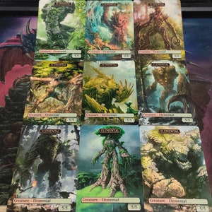May include: Nine trading cards featuring illustrations of green, brown, and gray elemental creatures. Each card has the word "Elemental" printed in a gold banner at the top and "Creature - Elemental" printed in black at the bottom. The cards are all 5/5.