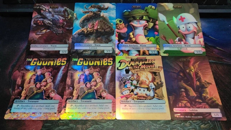 May include: A set of nine trading cards featuring characters from popular films, including "The Goonies" and "DuckTales: The Movie - Treasure of the Lost Lamp". The cards are holographic and have a colourful, cartoon-like style.