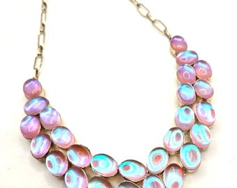 May include: A silver chain necklace with a double row of iridescent oval-shaped stones and a pendant of red stones.