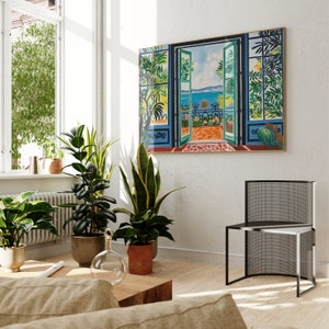 Puede incluir: Una pintura colorida de una puerta con vista a un oc&eacute;ano azul y un balc&oacute;n con plantas. La pintura est&aacute; enmarcada en un marco de madera y cuelga de una pared blanca. Hay plantas en macetas en primer plano.