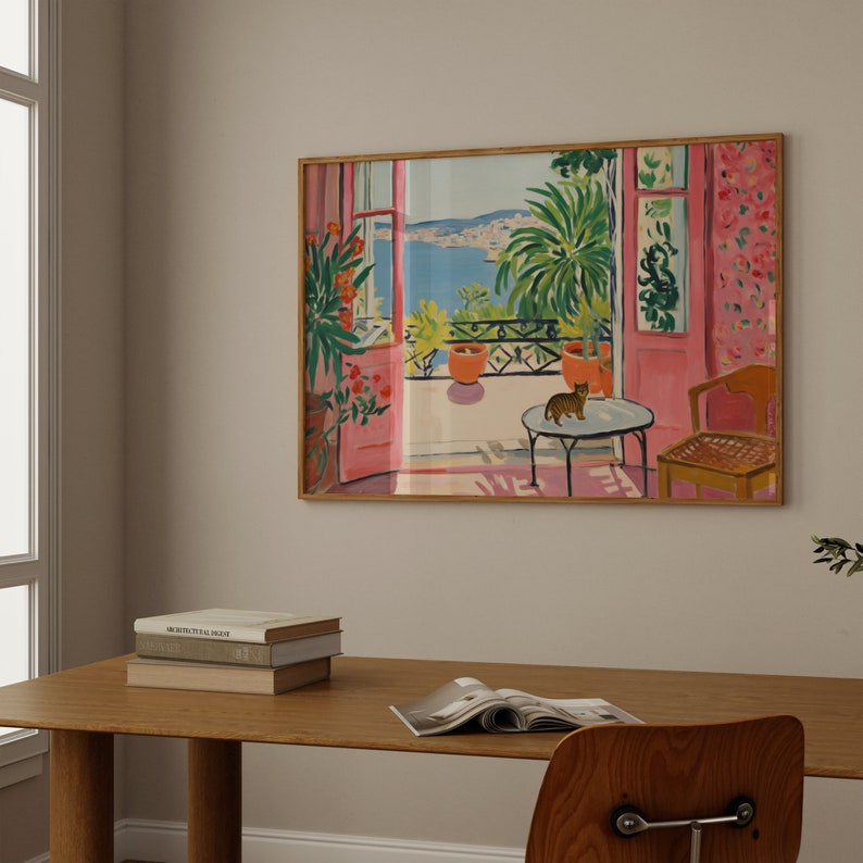 Puede incluir: Una pintura enmarcada de una habitaci&oacute;n rosa con una ventana que da a una masa de agua azul. La ventana est&aacute; abierta y hay un gato sentado en una mesa en la habitaci&oacute;n. La pintura est&aacute; en un marco de madera.