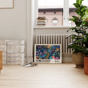 May include: A framed print of a painting by Yayoi Kusama. The painting depicts a whimsical garden with flowers, mushrooms, and a winding path. The text "Yayoi Kusama" and "Japan 1972" is printed at the bottom of the print.