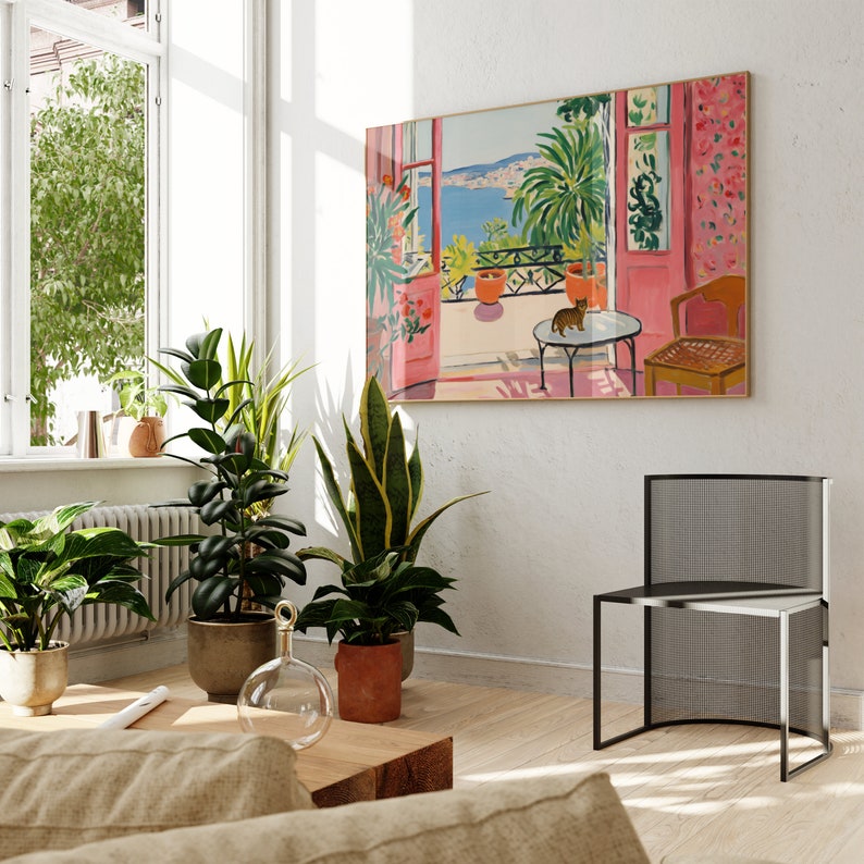 Puede incluir: Una pintura de una habitaci&oacute;n rosa y blanca con una ventana que da a un mar azul. La habitaci&oacute;n tiene una silla, una mesa y una planta en maceta. Un gato est&aacute; sentado en la mesa.