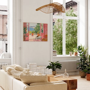 Puede incluir: Una pintura de una habitaci&oacute;n rosa y blanca con una ventana que da a un mar azul. La ventana est&aacute; abierta y hay un gato sentado en una silla en la habitaci&oacute;n. La pintura est&aacute; enmarcada y colgada en una pared blanca.