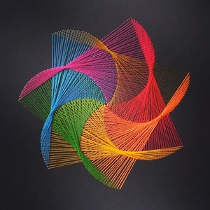 Puede incluir: Una pieza de arte de hilo colorido con un diseño de estrella. El arte está hecho con hilos de diferentes colores, incluyendo rojo, naranja, amarillo, verde, azul y morado.