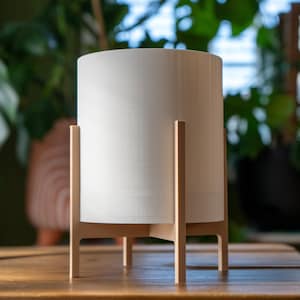 May include: White cylindrical planter with a wooden stand. The stand has four legs and a simple design.