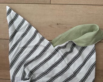 May include: A white and gray striped fabric bag with a green interior. The bag is folded, showing the striped exterior and the green lining. The bag is made of a soft fabric.