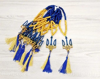 May include: A set of yellow and blue wooden prayer beads with a trident charm. The beads are strung on a cord and have a tassel at the end. The trident charm is a symbol of Ukraine.