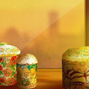 Może przedstawiać: Trzy ozdobne ciasta wielkanocne, jedno z motywem motyla, jedno z motywem kwiatowym, a jedno z motywem dziecięcym. Ciasta stoją na drewnianej powierzchni przed oknem.