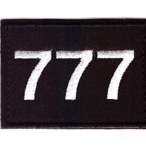 May include: Black rectangular patch with the number 777 embroidered in white. The patch has a black border and is likely made of fabric. The numbers are in a bold, sans-serif font.