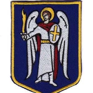Puede incluir: Parche bordado que representa una figura alada con un halo, sosteniendo una antorcha en llamas y un escudo con una cruz. El diseño está sobre un fondo azul con un borde dorado. La figura lleva una túnica blanca con detalles rojos.