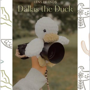 Può includere: Un giocattolo di peluche di anatra bianca all'uncinetto è attaccato a un obiettivo della fotocamera nero. La fotocamera è tenuta da una mano. Il testo "Lens Friends Dallas the Duck" è in alto nell'immagine e "Busy Little Bee Babies" è in basso nell'immagine.