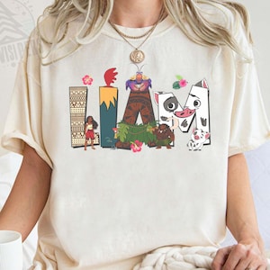 May include: Cream-coloured t-shirt featuring the word "LAVA" in colourful, cartoon-style lettering. The letters are decorated with images of characters and elements from a popular animated movie. The shirt is made of a soft, comfortable material.