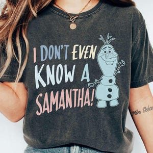 May include: Dark heather grey t-shirt with a graphic of Olaf from Frozen. The text on the shirt reads "I don't even know a Samantha!"