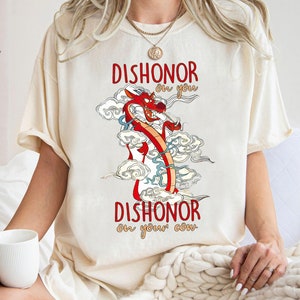 Puede incluir: Una camiseta de color crema con un gr&aacute;fico de drag&oacute;n rojo y el texto "Dishonor on you, Dishonor on your cow."