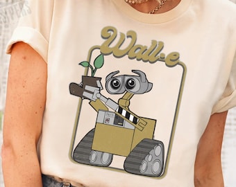May include: A beige t-shirt with a retro-style graphic of the robot WALL-E holding a plant. The text "Wall-e" is in a stylized font above the robot.