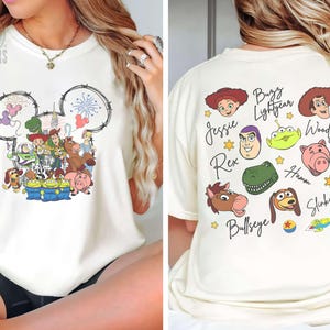 Pu&ograve; includere: T-shirt color crema con grafica a tema Disney sul davanti, con un contorno della testa di Topolino riempito di personaggi di Toy Story. Il retro mostra i volti e i nomi di vari personaggi di Toy Story.