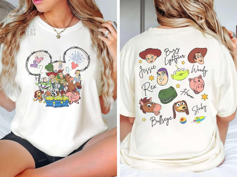 Pu&ograve; includere: T-shirt color crema con grafica a tema Disney sul davanti, con un contorno della testa di Topolino riempito di personaggi di Toy Story. Il retro mostra i volti e i nomi di vari personaggi di Toy Story.