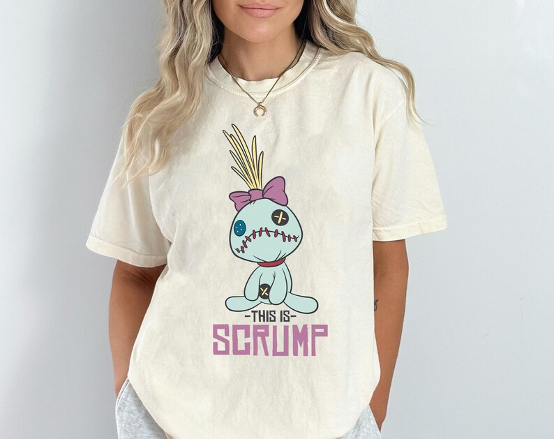 May include: A white t-shirt with a cartoon image of a blue and purple Stitch doll with the text "This is Scrump" printed on the front.