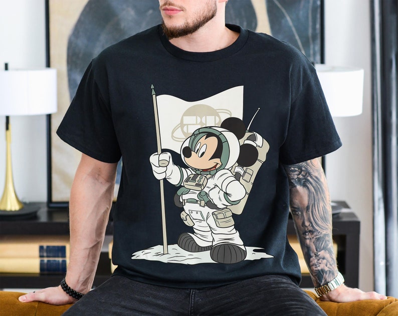 May include: Black t-shirt with a graphic of Mickey Mouse dressed as an astronaut holding a flag that says "Space Mountain".