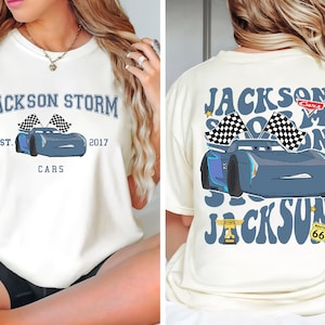 Può includere: Una maglietta bianca con una grafica blu e bianca di un'auto da corsa con il testo "JACKSON STORM EST. 2017 CARS" sul davanti e una grafica blu e bianca di un'auto da corsa con il testo "JACKSON STORM CARS" sul retro.