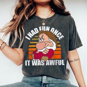 May include: A dark grey t-shirt with a vintage-style graphic of a grumpy cartoon dwarf with the text "I had fun once it was awful".