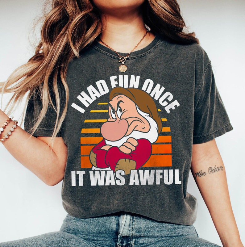 May include: A dark grey t-shirt with a vintage-style graphic of a grumpy cartoon dwarf with the text "I had fun once it was awful".