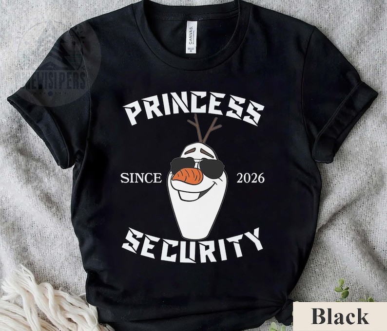 May include: Black t-shirt with a white graphic featuring a cartoon snowman wearing sunglasses and a carrot nose. The text reads "PRINCESS SECURITY SINCE 2026". The shirt is made of a soft material.