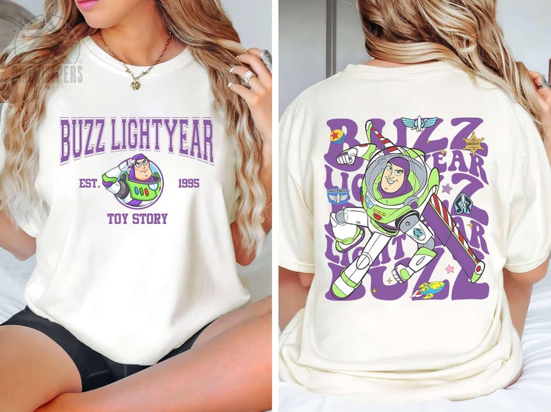 May include: Cream-colored t-shirt featuring Buzz Lightyear from Toy Story. The front displays "Buzz Lightyear" in purple arched text, with the character's image and "Est. 1995, Toy Story." The back shows Buzz in action with the same text.