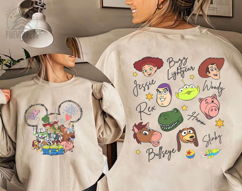 Pu&ograve; includere: Felpa beige con un design a testa di Topolino con personaggi di Toy Story. Il retro mostra i volti e i nomi dei personaggi, tra cui Buzz Lightyear, Woody e Jessie. Un design divertente e colorato.