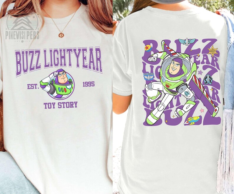 May include: White t-shirt featuring a Buzz Lightyear graphic from Toy Story. The front displays "Buzz Lightyear" in purple, with an image of Buzz and the text "Toy Story 1995". The back shows Buzz in action with the words "Buzz Lightyear".