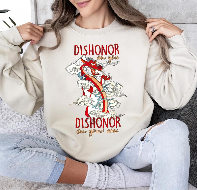 Puede incluir: Una sudadera de color crema con una ilustraci&oacute;n de un drag&oacute;n rojo y el texto "Dishonor on you Dishonor on your cow" impreso en ella.