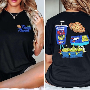 May include: Black t-shirt featuring the Pizza Planet logo on the front and a graphic of the Mega Gulp drink, pizza, Super Nova Burger, and the Little Green Men on the back. The shirt is a crew neck style.