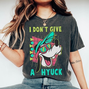 May include: A black t-shirt with a retro-style graphic of Goofy wearing sunglasses and a hat. The text "I don't give a hyuck" is printed on the shirt.