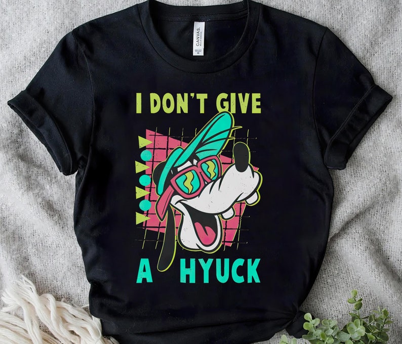 May include: Black t-shirt with a cartoon dog wearing sunglasses and a hat. The text "I don't give a hyuck" is printed on the shirt.