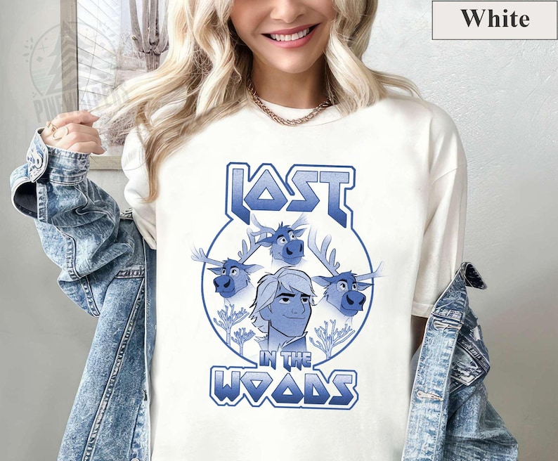 May include: White t-shirt with a blue graphic of a cartoon character with three reindeer. The graphic says "Lost in the Woods" in a stylized font.