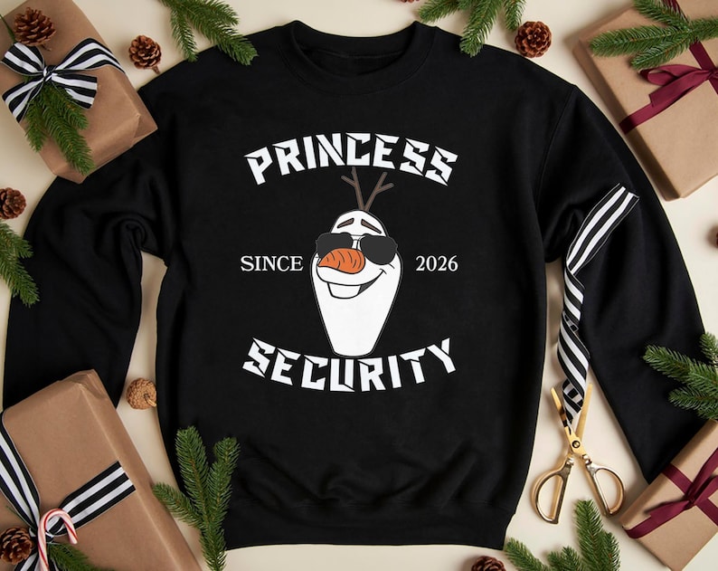 May include: Black sweatshirt with the text "PRINCESS SECURITY" and an illustration of Olaf wearing sunglasses. The text "SINCE 2026" is also included. The sweatshirt is surrounded by gift boxes, pine needles, and pine cones.