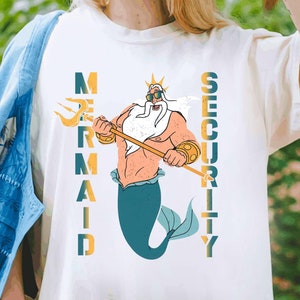 May include: White t-shirt with a graphic of King Triton from The Little Mermaid holding a trident. The text "Mermaid Security" is printed vertically on the shirt.