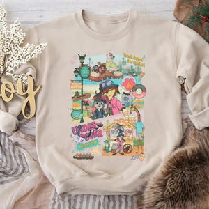 May include: Beige crewneck sweatshirt featuring a colorful cartoon graphic. The graphic includes various characters, signs, and the text "Undercover Mission" and "Track down the spike!"