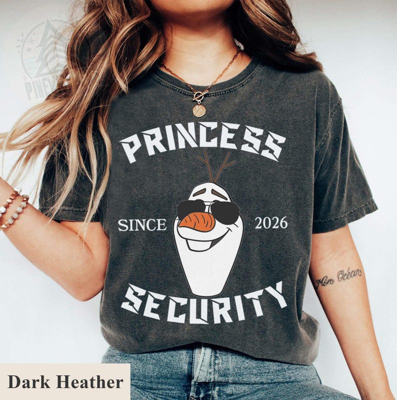 May include: Dark heather gray t-shirt featuring a graphic of Olaf from Frozen wearing sunglasses. The text reads "PRINCESS SECURITY SINCE 2026". A fun and playful design for fans of the movie.