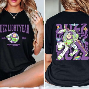 May include: Black t-shirt featuring a graphic of Buzz Lightyear from Toy Story. The front design includes the text "Buzz Lightyear" in purple, with "Est. 1995" and "Toy Story" below. The back has a larger Buzz Lightyear graphic and text.